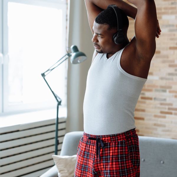 Smiling person stretching near a window at sunrise.